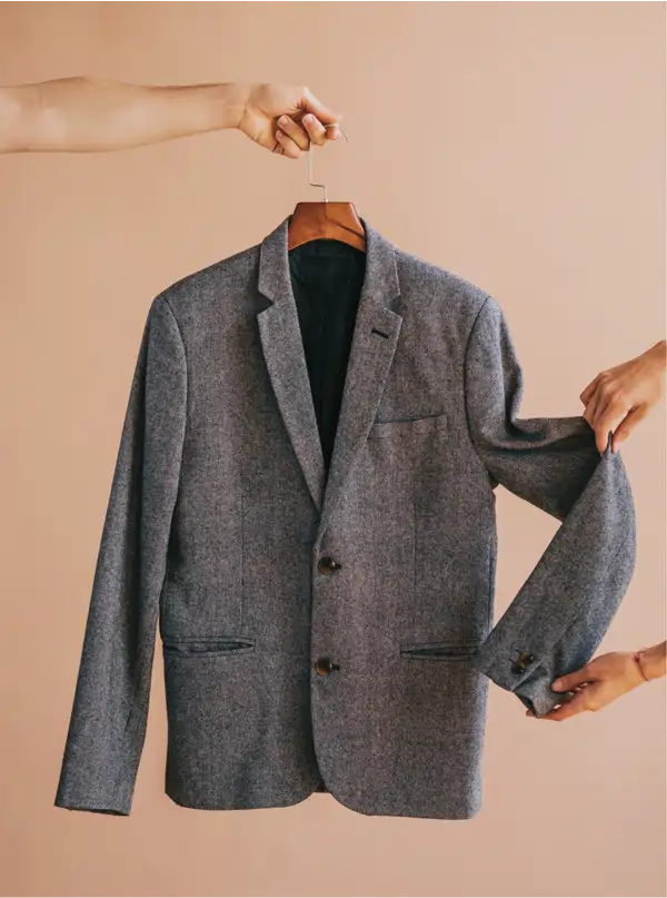 Blazer gris ajustado a la medida colgado en percha en La Clínica del Bluyín